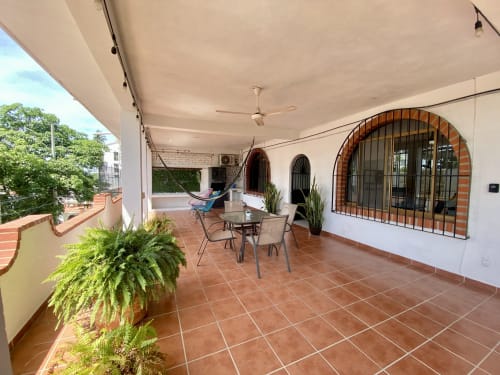 Spacious terracotta-tiled balcony at Anita Ocean View apartment in Puerto Vallarta with sea views, hammock, dining table, and
