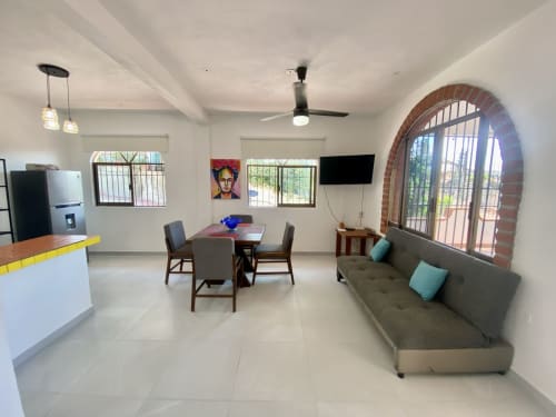 Open-plan apartment at Anita Ocean View, Puerto Vallarta featuring dining area, sofa, kitchen, and arched brick doorway to