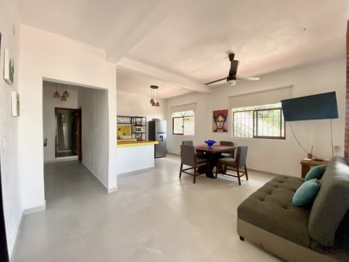 Anita Ocean View apartment in Puerto Vallarta with open living area, dining table, grey sofa, kitchen, and sea view windows