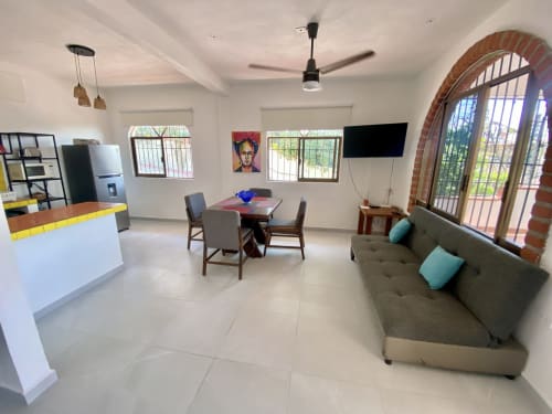 Modern apartment living area at Anita Ocean View in Puerto Vallarta with sofa, dining table, kitchen, and sea view balcony