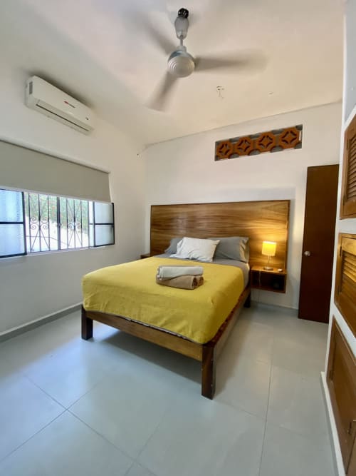 Modern bedroom at Anita Ocean View, Puerto Vallarta with wooden bed, yellow bedding, AC unit, and sea view window