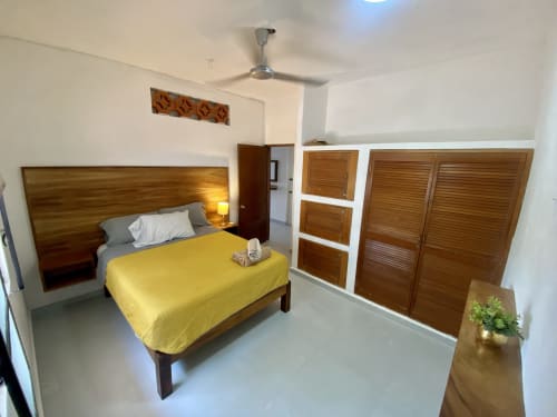 Spacious bedroom at Anita Ocean View Puerto Vallarta with wooden bed, yellow bedding, and wooden storage cabinets