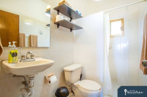 Clean bathroom in Anita apartment, Puerto Vallarta with sink, toilet, shower and white tile walls