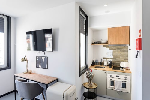 Pequeña cocina compacta con encimera de madera, estufa de gas y espacio de trabajo junto al área de escritorio en Benefit Collection Porto