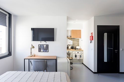 Estudio compacto en Benefit Collection Porto con cama, escritorio, TV de pared y cocina americana con amenidades modernas