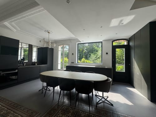 Modern dining area in Villa Saint-Hilaire with oval white table, black chairs, kitchen, and garden views