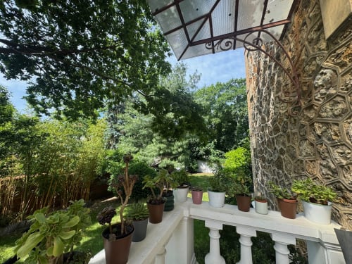 Terrace garden view at Villa Saint-Hilaire, Locavilla hotel in Colombes with potted plants and ornate stone wall