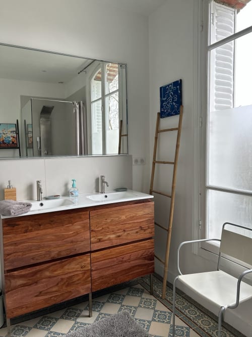 Modern bathroom in Villa Saint-Hilaire with wooden vanity, dual sinks, mirror, ladder shelf, and patterned floor tiles