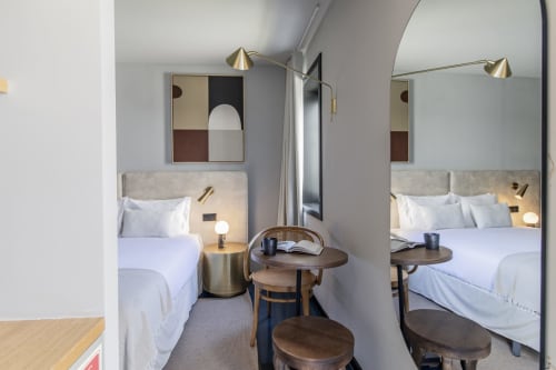 Compact studio bedroom at Benefit Collection Porto with twin beds, mirrors, brass lighting, and modern minimalist design