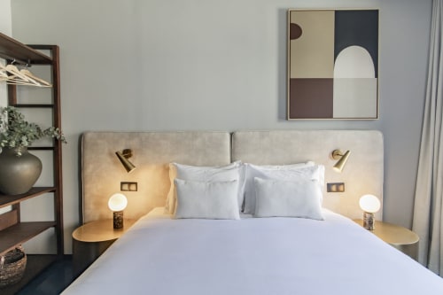 Modern studio bedroom at Benefit Collection Porto with white bedding, brass fixtures, contemporary art, and garden views