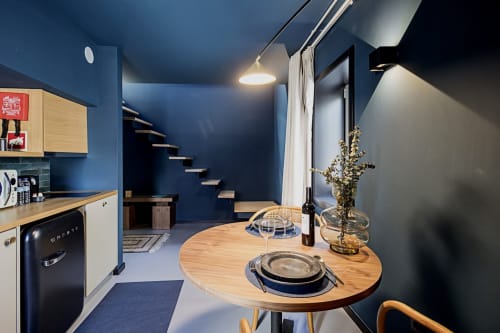 Estúdio duplex moderno com kitchenette e área de refeições, paredes azuis, mesa de madeira, escada, quarto de hotel no Porto