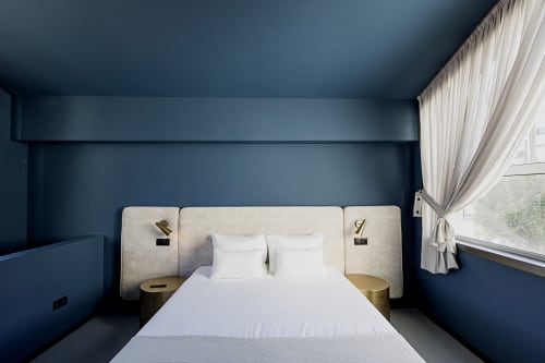 Quarto moderno em hotel no Porto com paredes azul-petróleo escuro, cabeceira cor creme, roupa de cama branca e vista para a cidade pela janela com cortinas
