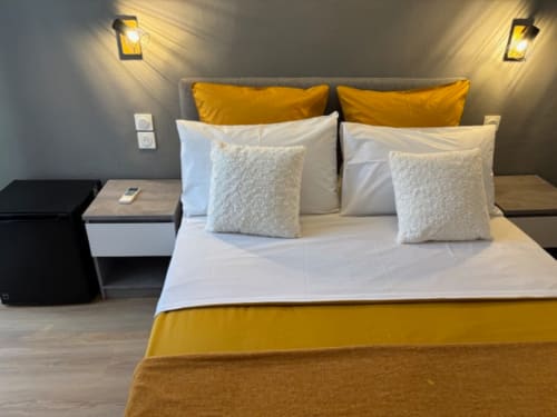 Modern double bedroom at Hôtel Manon Marseille with yellow and white bedding, grey headboard, and ambient lighting