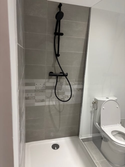 Modern bathroom at Hôtel Manon Marseille with walk-in shower, black fixtures, and white toilet