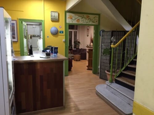 Hôtel Manon hallway in Marseille with yellow walls, green doorframes, wooden counter, and stairs