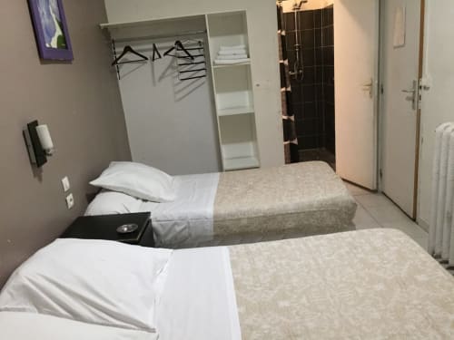 Chambre triple à l'Hôtel Manon à Marseille avec deux lits, armoire et salle de bains attenante