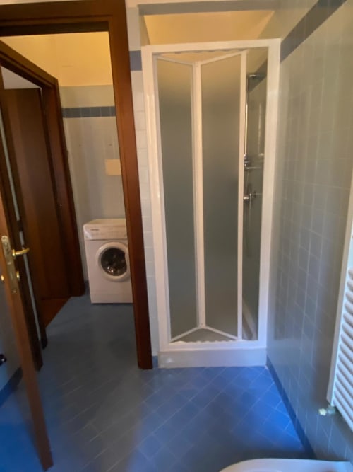 Bathroom hallway at Alloggio Le Casette, Verona, with shower enclosure, washing machine, and accessible facilities