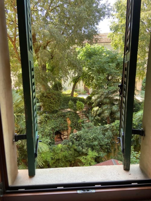 Lush garden view from apartment window at Alloggio Le Casette, Verona with green courtyard and trees