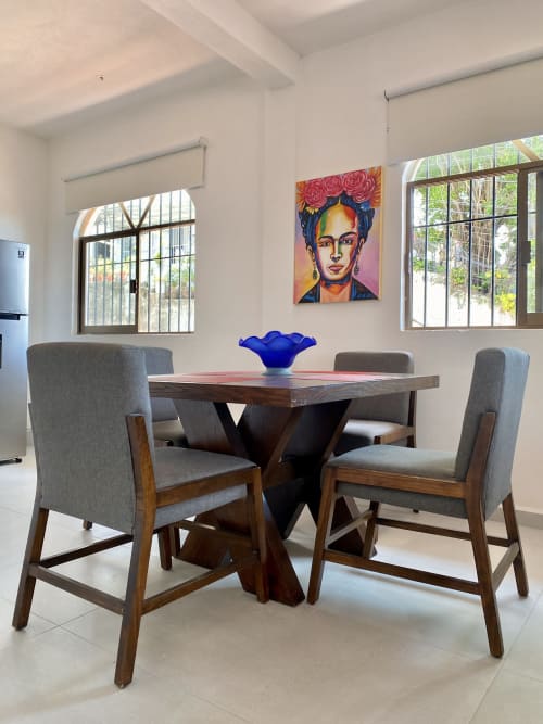 Modern dining area at Anita Ocean View with wooden table, gray chairs, colorful portrait, and natural light from windows