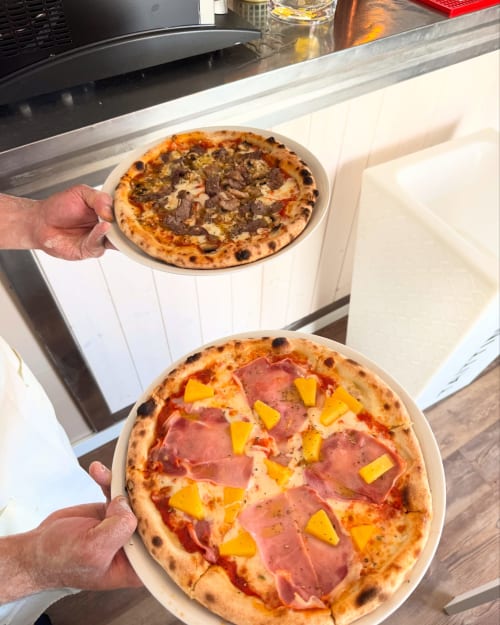 Two freshly baked pizzas held at Costa Alentejana B&B in Zambujeira do Mar