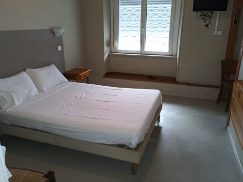 Chambre d'hôtel impeccable à la Résidence Soansa du Gérardmer avec lit blanc, télévision et vue sur la ville
