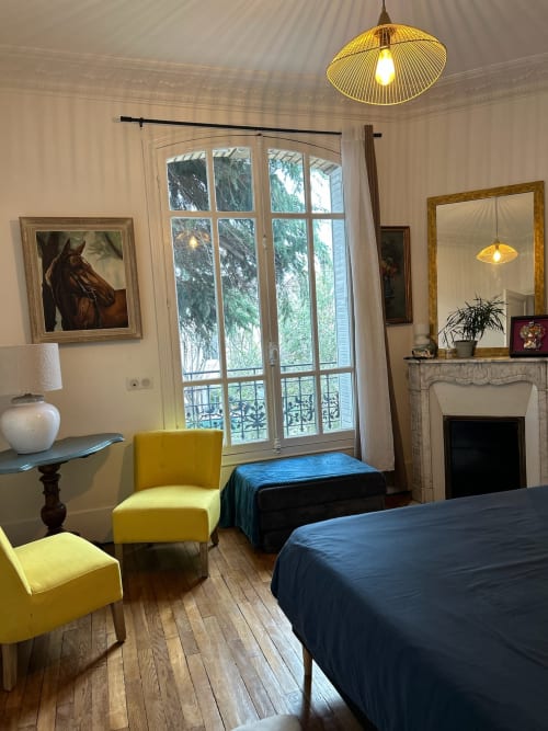 Elegant bedroom with yellow chairs, fireplace, and garden view doors at Villa Saint-Hilaire in Colombes
