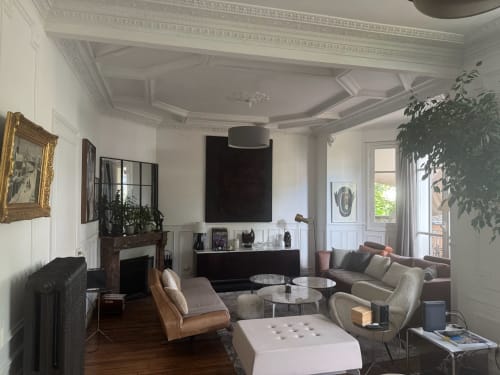 Elegant living room at Villa Saint-Hilaire in Colombes with coffered ceiling, modern furnishings, fireplace, and garden views