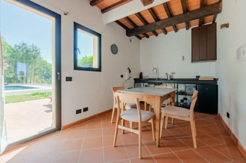 Moderno spazio cucina-pranzo in Tenuta Alela Deluxe Apartment con vista sulla piscina, con tavolo in legno, sedie e accesso a