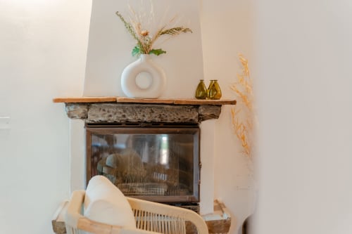 Camino di Tenuta Alela decorato con vaso bianco, fiori secchi e oggetti di design