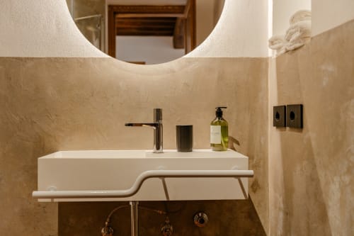 Lavabo moderno con specchio rotondo e pareti in marmo presso l'hotel Tenuta Alela a Figline Valdarno, Italia