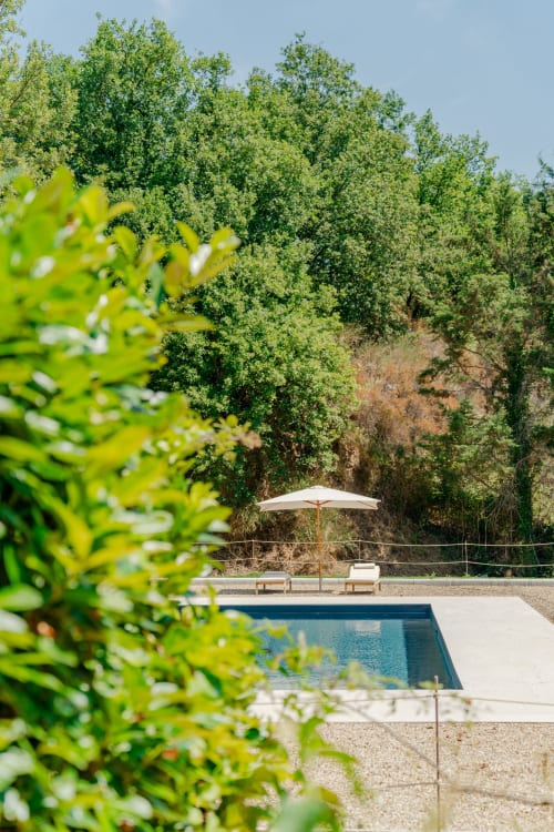 Area piscina in stile toscano presso Tenuta Alela con ombrellone, lettini e sfondo di colline boscose a Figline Valdarno