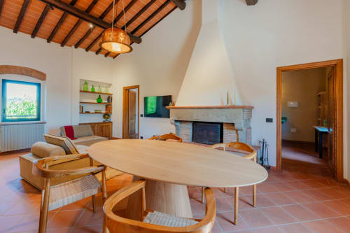 Ampio soggiorno dell'Apartment Camino a Tenuta Alela con tavolo ovale, camino, travi in legno e vista sul giardino