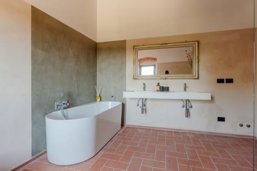 Bagno moderno di Tenuta Alela con vasca da bagno, doppio lavabo, specchio decorativo e pavimento in cotto