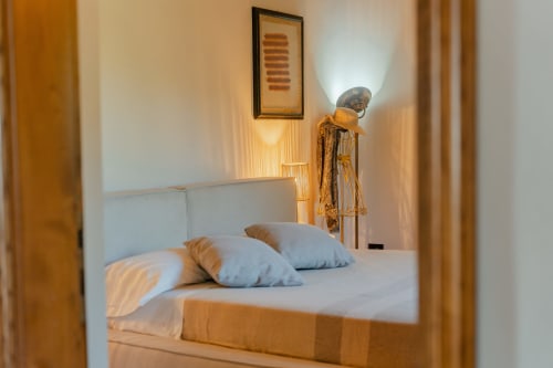 Camera da letto elegante di Tenuta Alela con testata bianca, cuscini blu e arredi raffinati a Figline Valdarno
