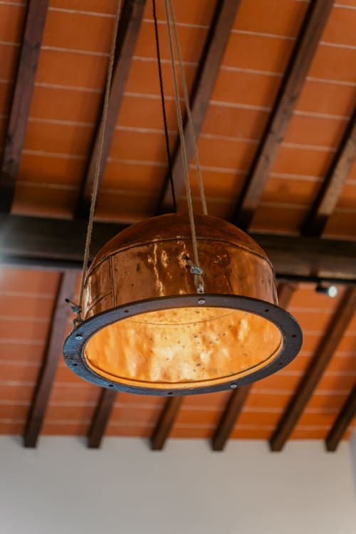 Lampada a sospensione in rame rustico appesa al soffitto in legno dell'appartamento Tenuta Alela a Figline Valdarno, Italia