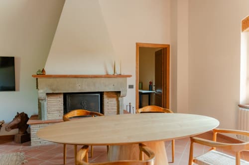 Moderna zona pranzo dell'Appartamento Camino di Tenuta Alela con tavolo in legno, camino e vista sul giardino in Toscana
