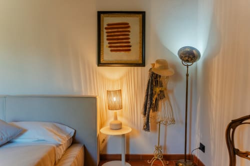 Camera da letto presso l'appartamento Tenuta Alela in Toscana con letto, lampada da comodino, attaccapanni, lampada a stelo e arte astratta incorniciata