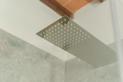 Moderna soffione doccia quadrato montato sul soffitto bianco nel bagno della suite luxury di Tenuta Alela, Figline Valdarno