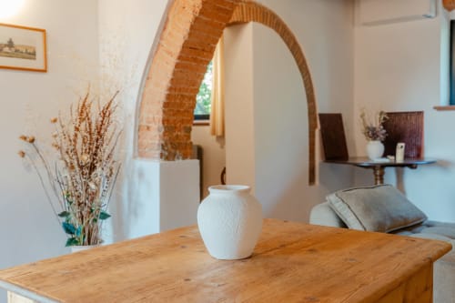 Tavolo da pranzo in legno rustico con vaso in ceramica bianca nell'Appartamento Deluxe di Tenuta Alela, Figline Valdarno, con mattoni a vista