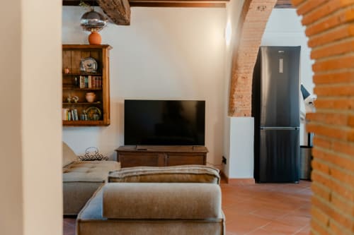 Zona giorno della Suite Deluxe con camera da letto a Tenuta Alela, Figline Valdarno, con TV, arredamento in legno, divano e cucina