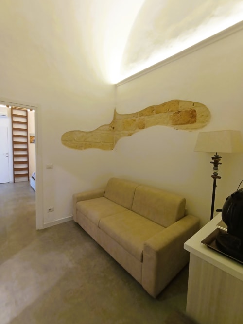Luminosa camera moderna al Bari Vacation B&B con divano color crema, arte murale in legno, lucernario e arredamento contemporaneo
