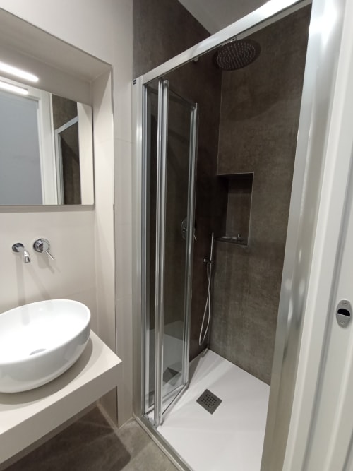 Moderno bagno della Bari Vacation B&B con lavabo bianco, cabina doccia in piastrelle scure e soffione pioggia