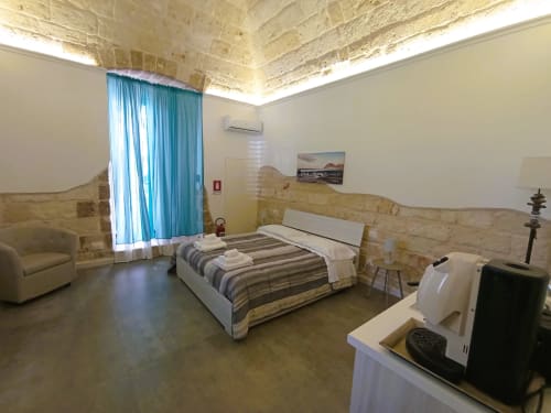 Camera moderna a Bari Vacation con biancheria a righe, tende turchesi, dettagli in pietra e vista sul mare nello storico San