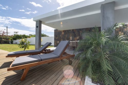Modern villa terrace with wooden loungers, potted palms, and manicured lawn at La Villa Boz, France