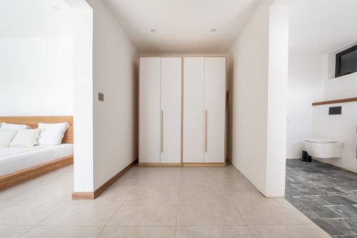 Modern villa bedroom with wooden bed, white wardrobe, and ensuite bathroom at La Villa Boz, Saint Philbert de Bouaine