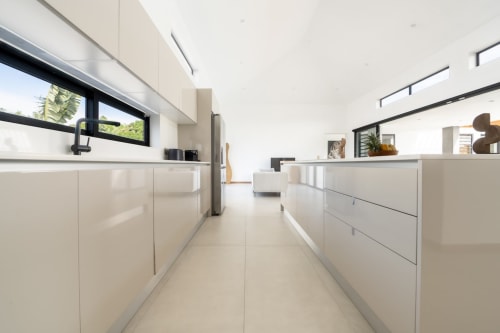 Modern white kitchen with island at La Villa Boz villa, Saint Philbert de Bouaine, featuring induction stove and stainless