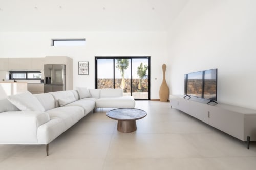 Modern living room at La Villa Boz with curved white sofa, round marble table, TV, and views of Saint Philbert de Bouaine