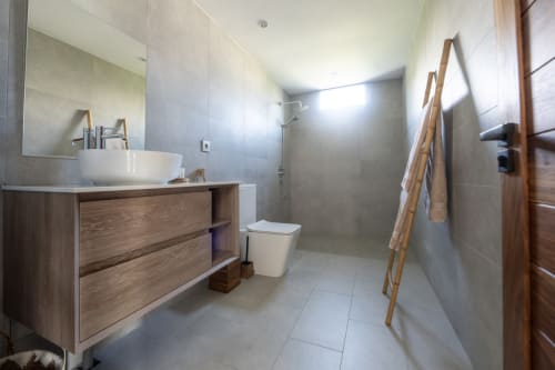 Modern bathroom at La Villa Boz villa with wooden vanity, round sink, toilet, and walk-in shower with wooden ladder towel