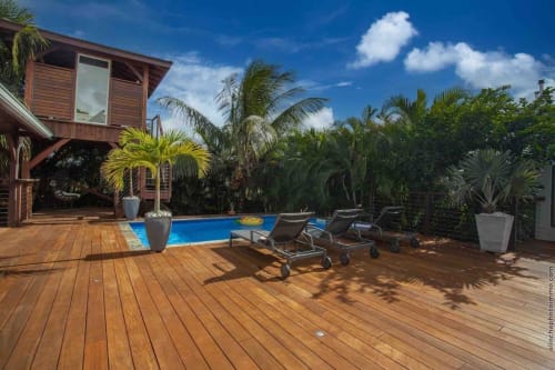 Tropical villa in Fort-de-France with wooden deck, private heated pool, lounge chairs, and lush palm trees