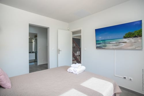 Modern bedroom in Paradise Location villa, Fort-de-France with beach artwork, ensuite bathroom access, and pool views
